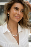 Woman wearing a white blouse and pearl necklace with blurred background