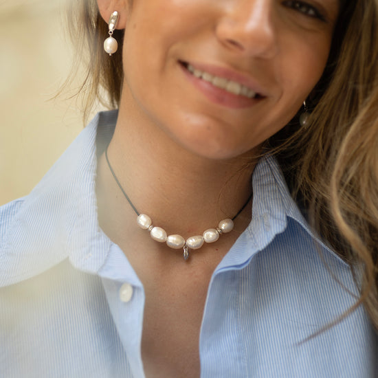 Woman wearing a pearl necklace and earrings with a blurred background