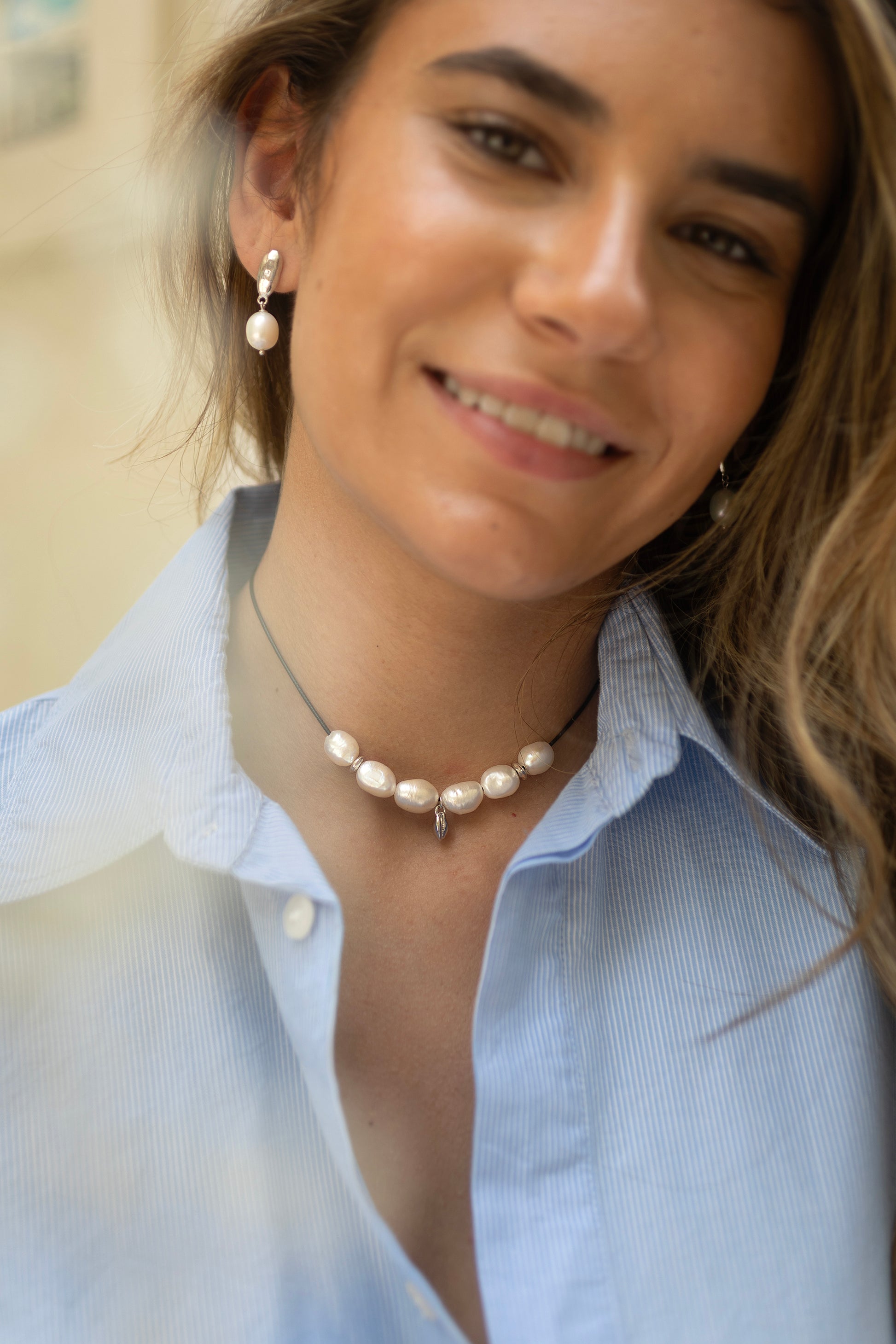 Woman wearing a pearl necklace and earrings with a blurred background
