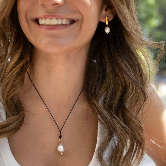 Woman wearing a necklace with a pearl pendant outdoors