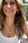 Woman wearing a necklace with a pearl pendant outdoors