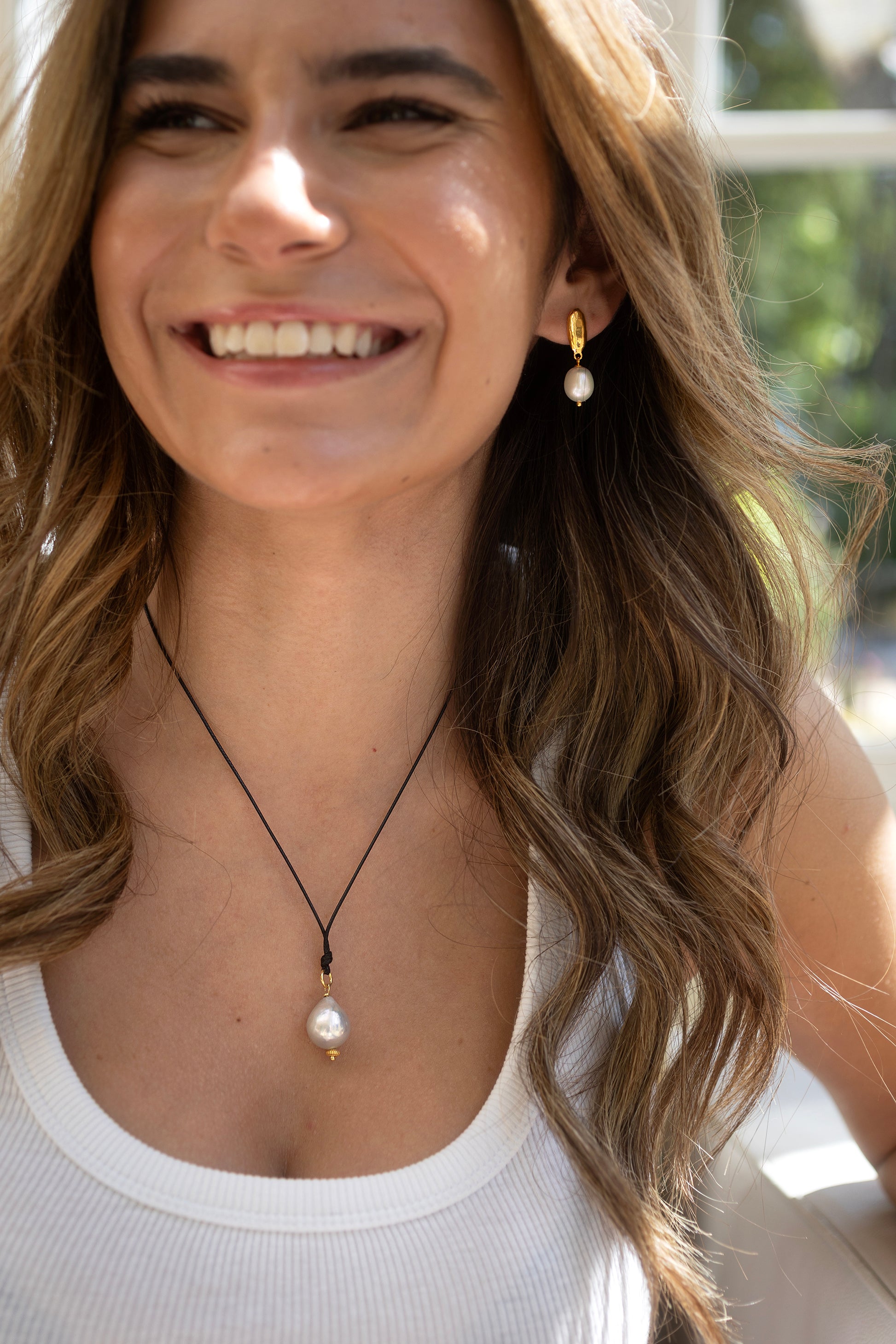 Woman wearing a necklace with a pearl pendant outdoors