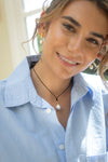 Woman wearing a light blue shirt with a pearl necklace and earrings.