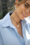 Woman wearing a pearl necklace and earrings with a blurred natural background