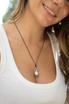Woman wearing a necklace with a pearl pendant outdoors