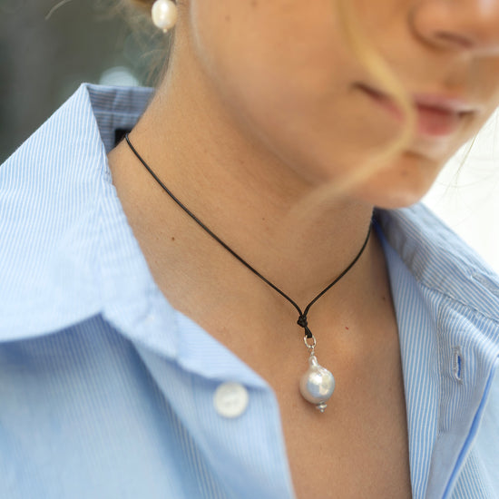 Close-up of a person wearing a necklace with pearl pendants.