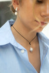 Close-up of a person wearing a necklace with pearl pendants.