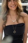 Woman wearing a black strapless top and pearl necklace with a blurred background