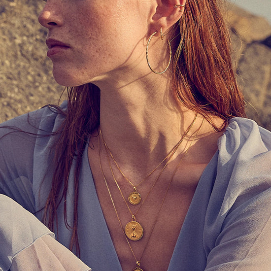 Woman wearing gold necklaces and earrings outdoors
