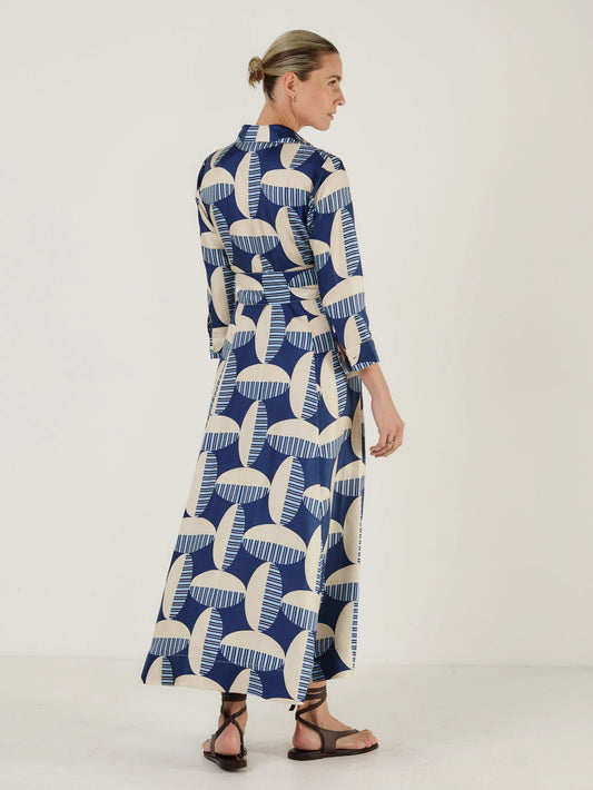 Woman wearing a long blue and white patterned dress from Mondo Corsini on a white background. Rear View