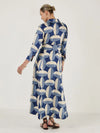 Woman wearing a blue and white patterned dress on a white background. Rear view opposite side