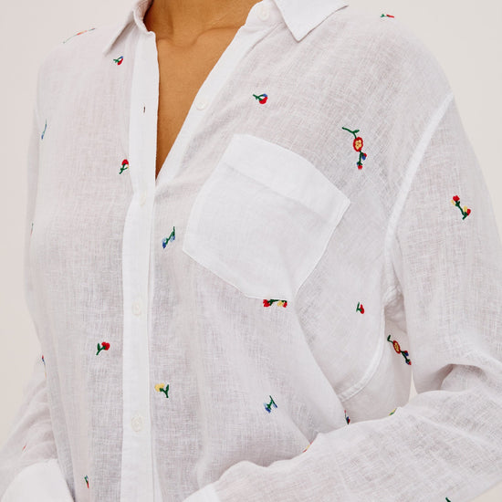 White shirt with colorful embroidered designs on a plain background