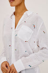 White shirt with colorful embroidered designs on a plain background