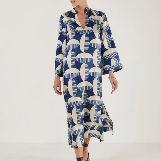 Woman wearing a blue and white patterned kaftan dress from Mondo Corsini on a white background
