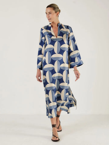 Woman wearing a blue and white patterned kaftan dress from Mondo Corsini on a white background