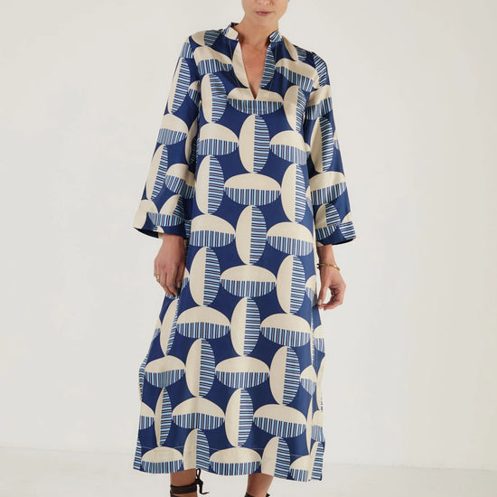 Woman wearing a blue and white patterned kaftan dress from Mondo Corsini on a white background. Straight on