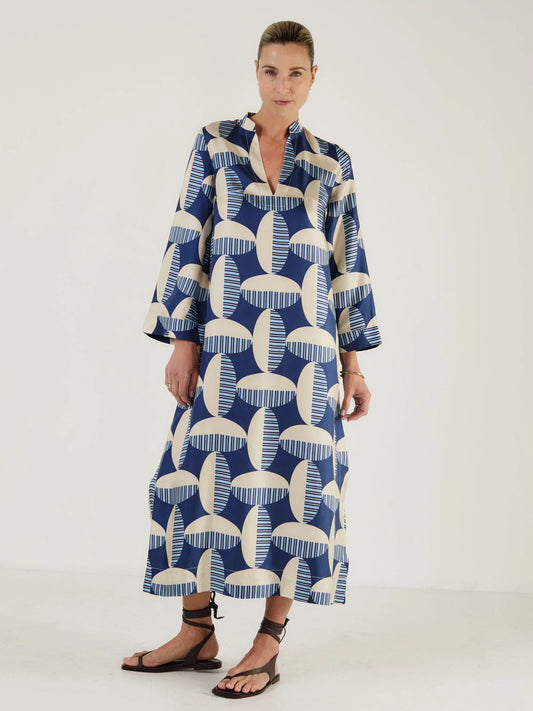 Woman wearing a blue and white patterned kaftan dress from Mondo Corsini on a white background. Straight on