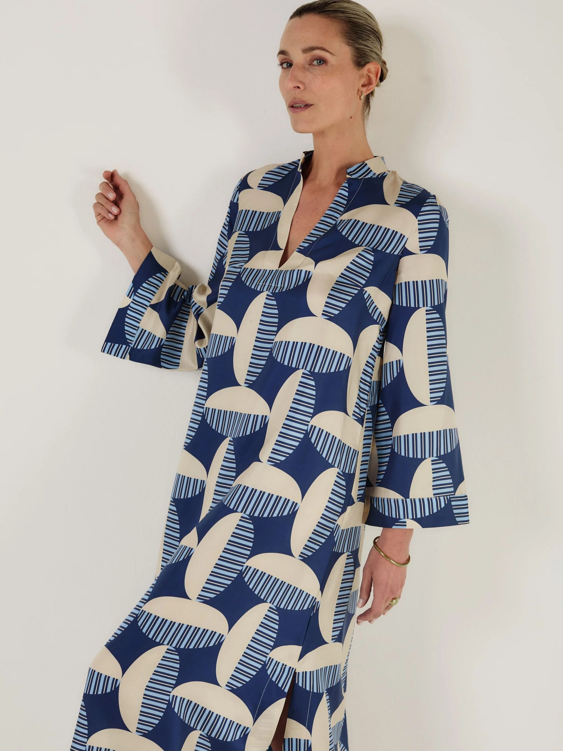 Woman wearing a blue and white patterned kaftan dress from Mondo Corsini on a white background. Close up