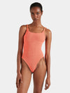 Woman wearing a coral one-piece swimsuit on a white background