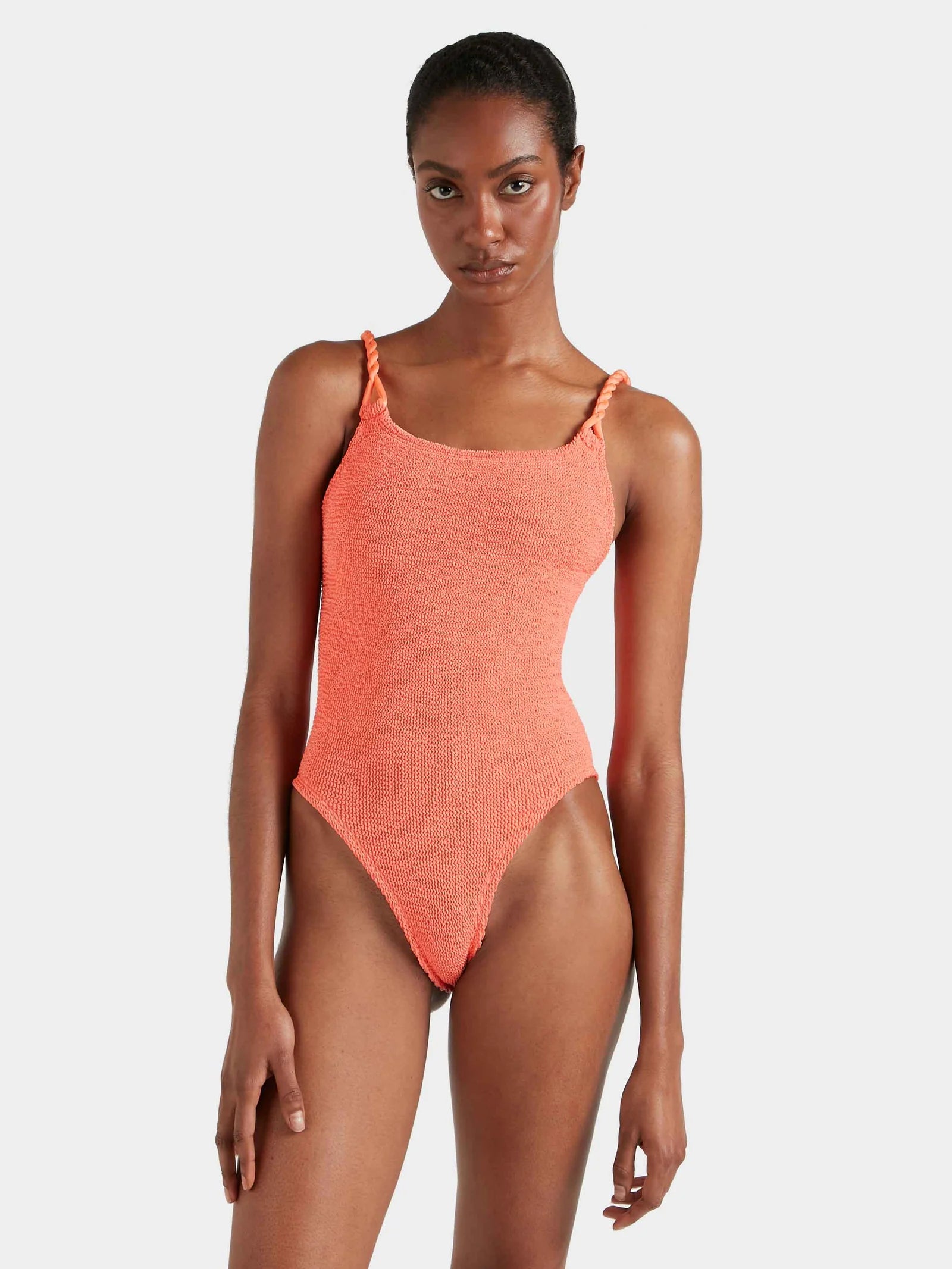 Woman wearing a coral one-piece swimsuit on a white background