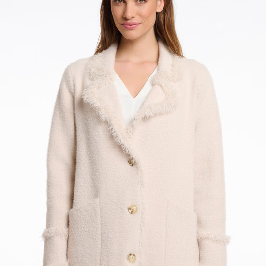 pale pink fluffy long cardigan which comes just above the knee with fringe detailing patch pockets and long sleeves close up