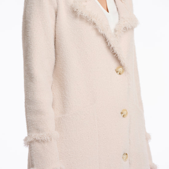 pale pink fluffy long cardigan which comes just above the knee with fringe detailing patch pockets and long sleeves side view