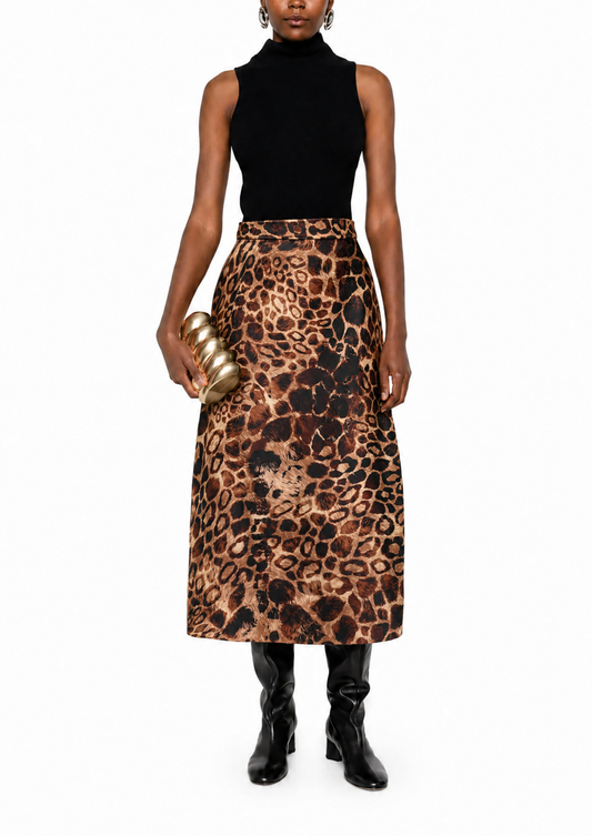A model wearing a sleeveless black mock-neck top and a high-waisted leopard-print midi skirt, holding a gold metallic clutch, set against a plain white background.