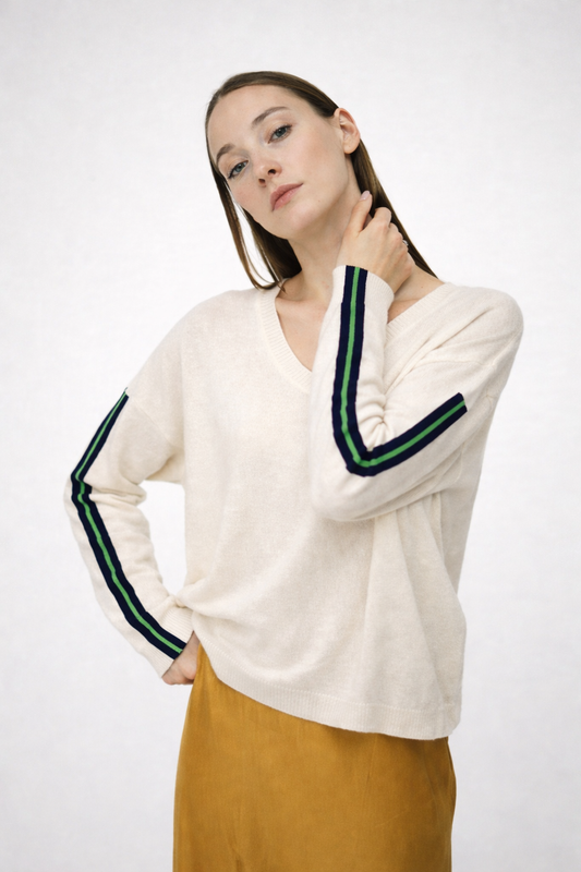 Woman wearing a white sweater with green and blue stripes on a white background