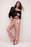 Woman wearing a black top and pink patterned satin trousers against a white background from ba&sh