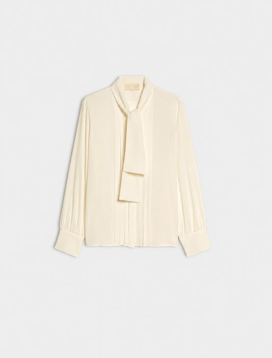 A cream long-sleeve blouse with a draped tie-neck detail, shown flat against a light gray background.