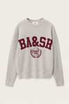 A light gray heather crewneck sweatshirt featuring a maroon'BA&SH' graphic and a circular crest on the front, displayed against a light off-white background.