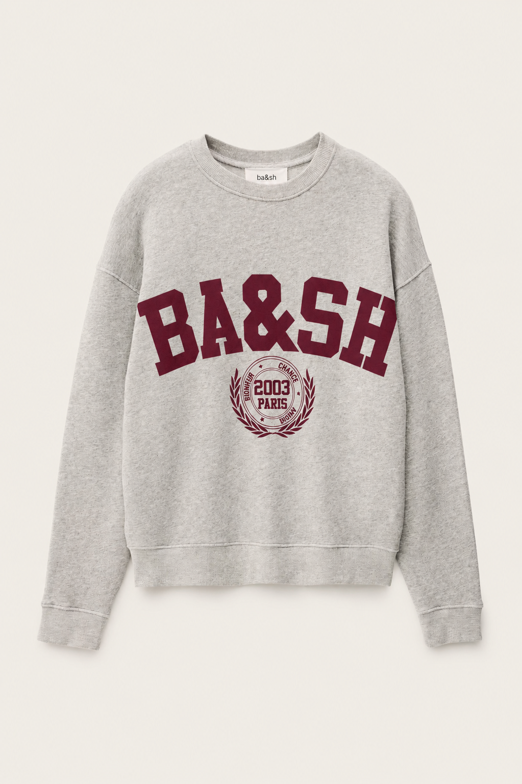 A light gray heather crewneck sweatshirt featuring a maroon'BA&SH' graphic and a circular crest on the front, displayed against a light off-white background.