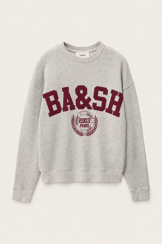 A light gray heather crewneck sweatshirt featuring a maroon'BA&SH' graphic and a circular crest on the front, displayed against a light off-white background.