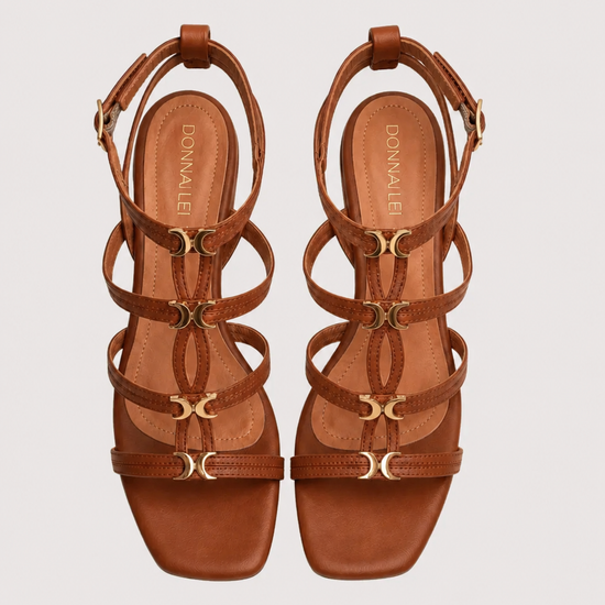 Pair of brown strappy sandals on a light gray background