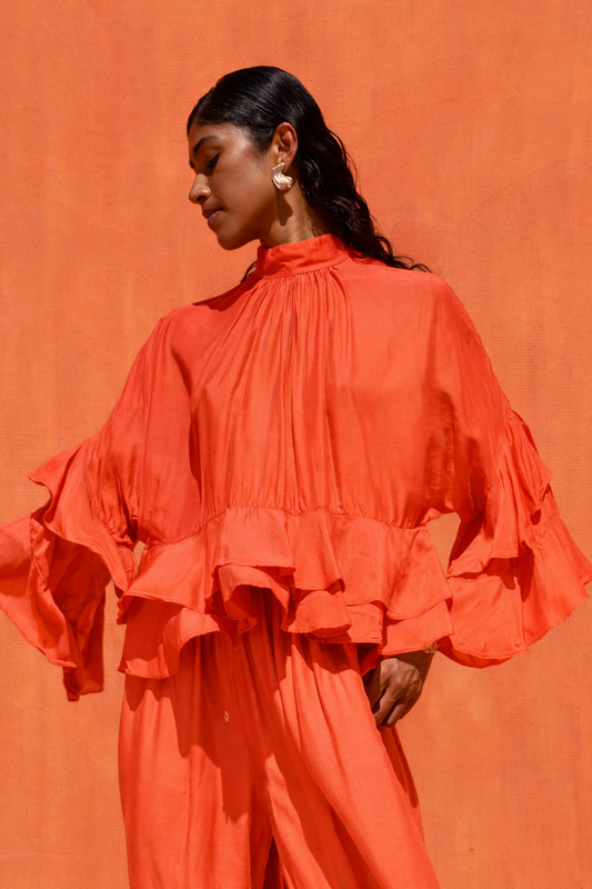 Woman wearing an orange ruffled outfit against an orange background