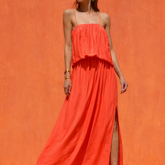 Woman wearing a bright orange dress against an orange background