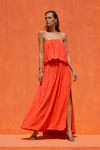 Woman wearing a bright orange dress against an orange background