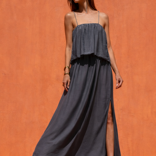 Woman wearing a long dark dress against an orange wall
