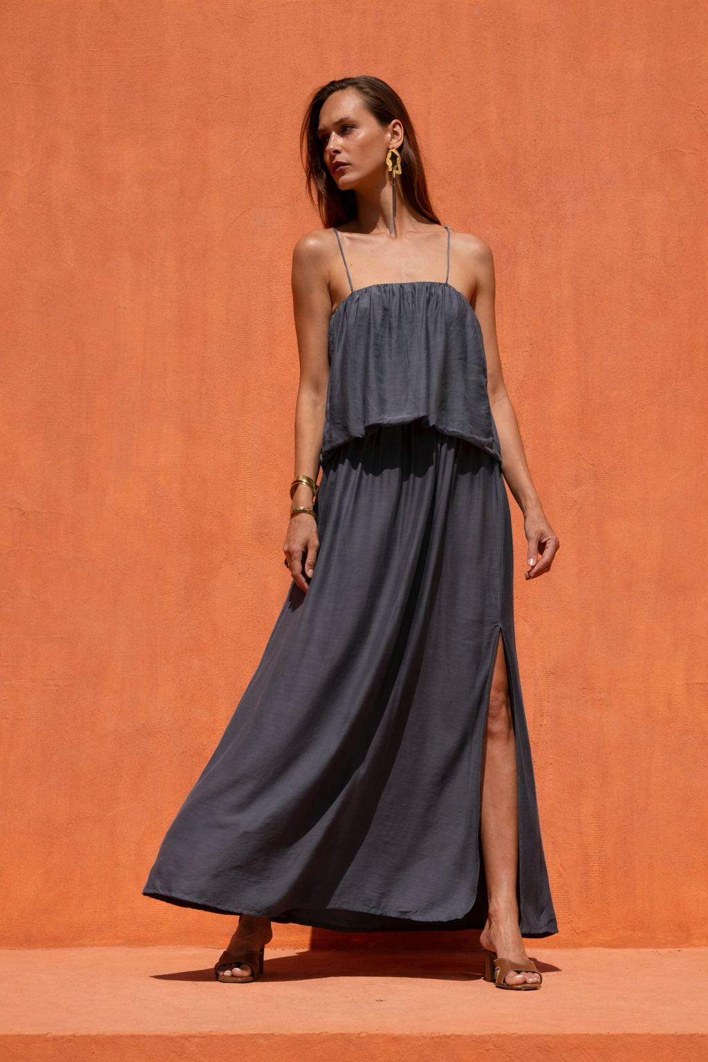 Woman wearing a long dark dress against an orange wall