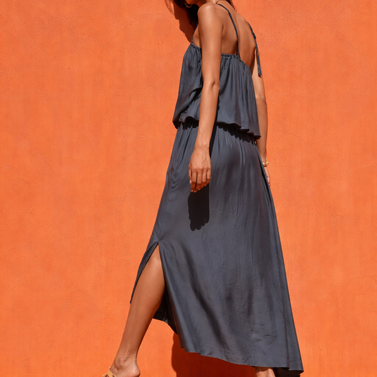 Woman in a blue dress standing against an orange background