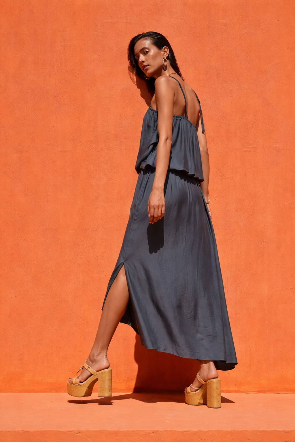 Woman in a blue dress standing against an orange background