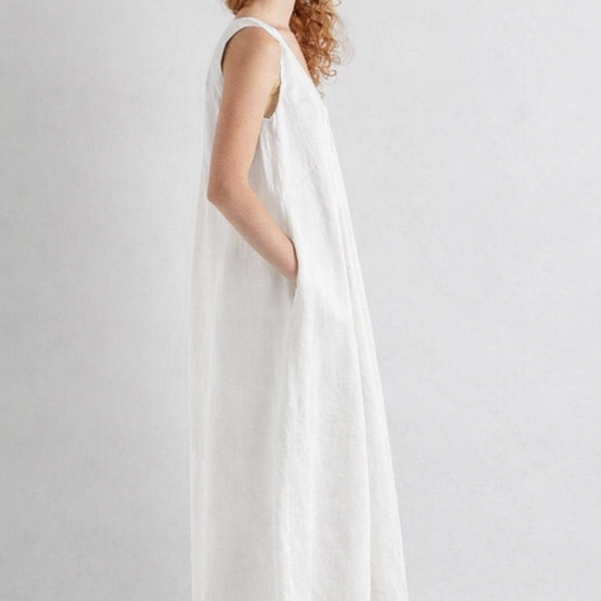 Woman wearing a white sleeveless dress on a plain background