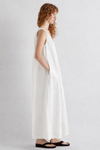 Woman wearing a white sleeveless dress on a plain background