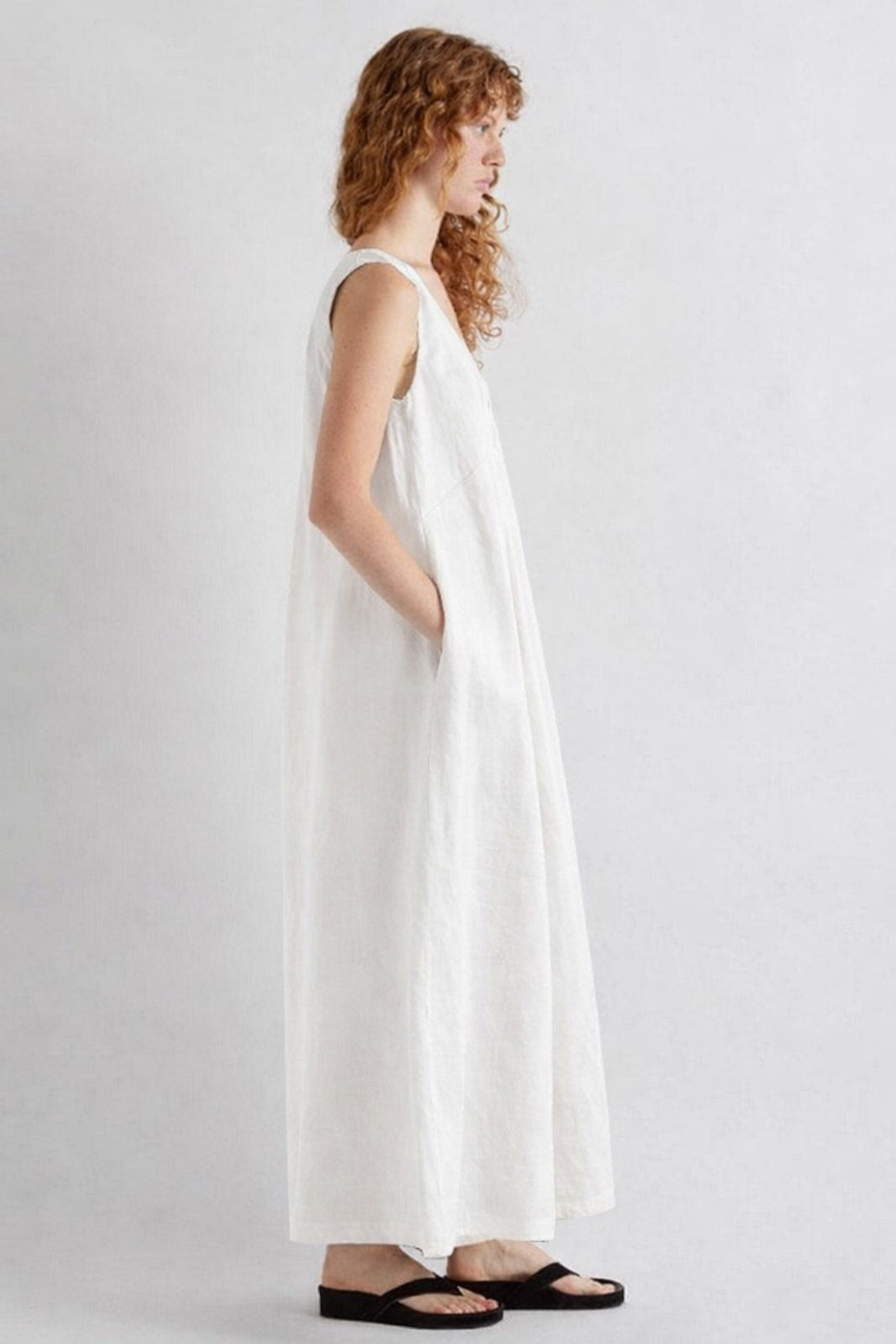 Woman wearing a white sleeveless dress on a plain background