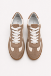 Pair of brown sneakers with white laces on a light gray background