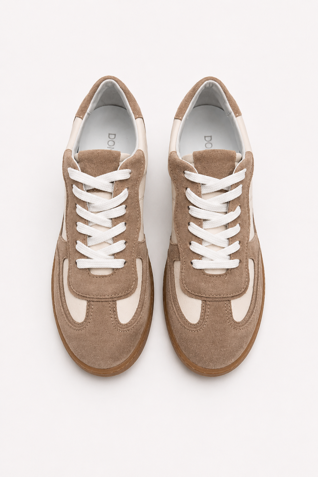 Pair of brown sneakers with white laces on a light gray background