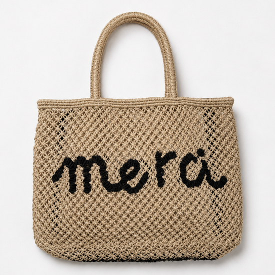 Product shot of woven bag with navy slogan on it on a white background.
