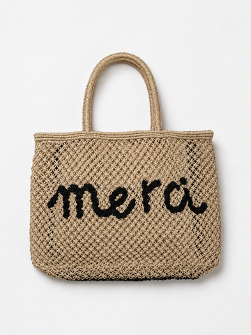 Product shot of woven bag with navy slogan on it on a white background.