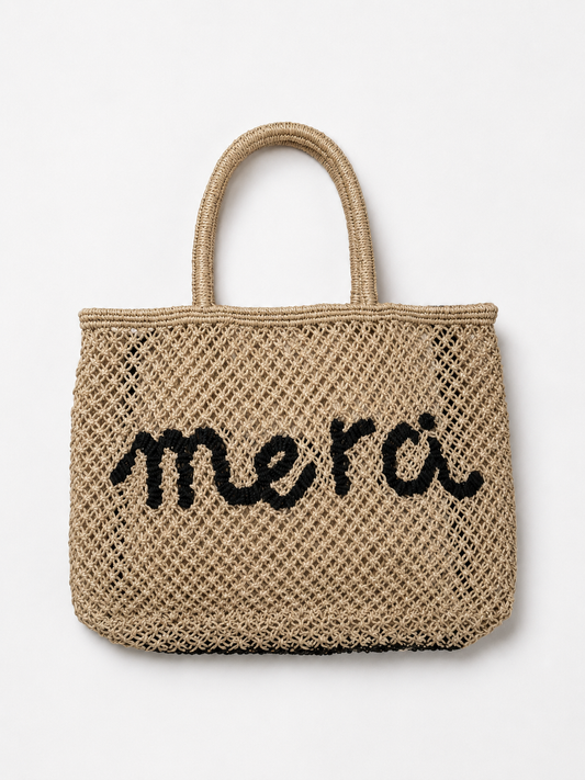 Product shot of woven bag with navy slogan on it on a white background.
