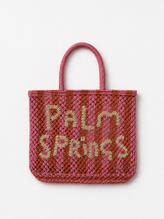 Pink and orange woven bag with 'Palm Springs' text on a white background